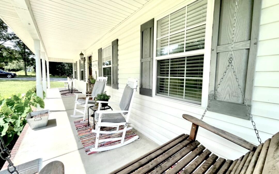 Photo of a porch with a swing and white painted rocking chairs