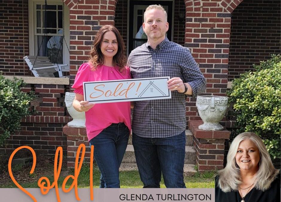 Photo of a couple holding a South State Realty "sold sign" by agent, Glenda Turlington