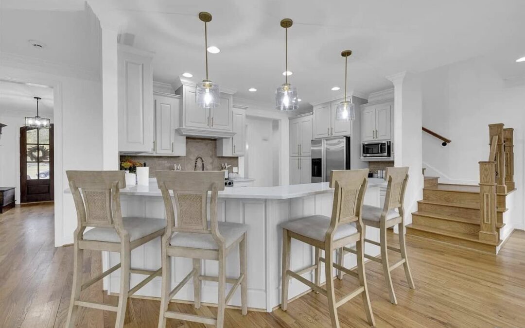 Photo of an open floor plan kitchen with a large eat in bar and drop lighting. The floors are polished wood