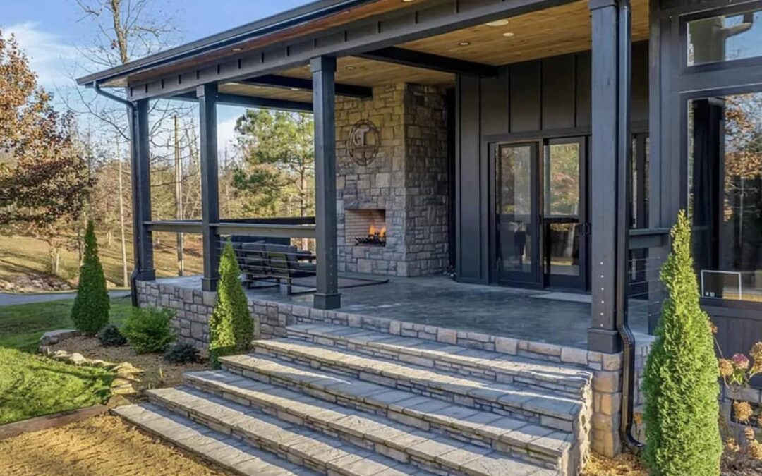 Photo of the entrance to a home that incorporates an outdoor fireplace, stone porch and steps and glass doors