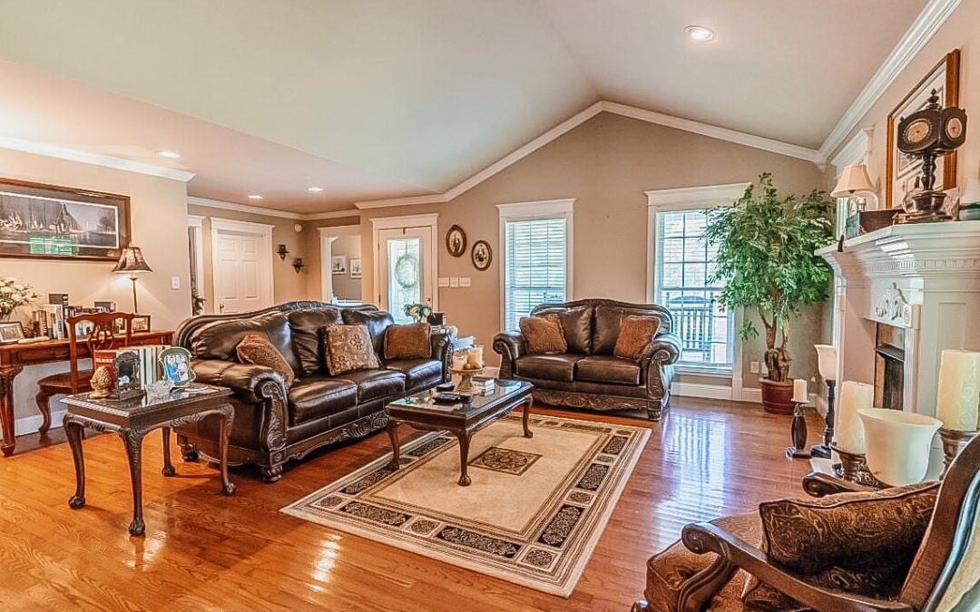 Photo of a living room with heavy leather couches, wood shining floors and a fireplace